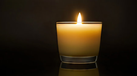 A glowing candle with a soft, steady flame, isolated on a black background for a calm, peaceful ambiance.の素材