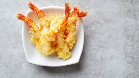 A minimalist food styling shot featuring shrimp tempura on a white dish, placed on a soft grey background.の素材