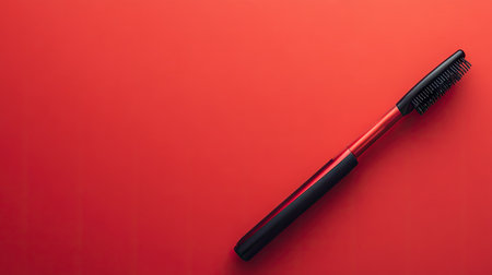 A modern curling wand and flat iron resting on a bold red background, emphasizing contrast.の素材