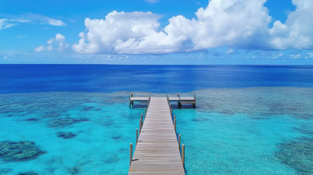A picturesque wooden pier leading out into the deep blue sea under a partly cloudy sky.の素材