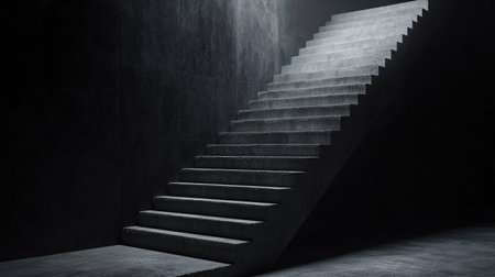 A mysterious concrete staircase ascending into pitch-black darkness, with faint light at the base.の素材