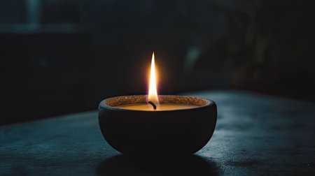 A single flickering candle flame against a dark, moody black background, creating a tranquil and intimate vibe.の素材