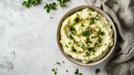 A classic comfort food shot of mashed potatoes with fresh parsley in a bowl, placed against a neutral white background for a clean, appetizing look.の素材