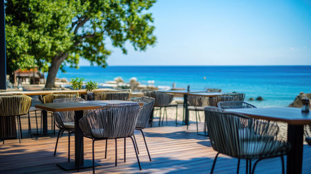 A beach caf with modern chairs and tables on a wooden deck, offering a panoramic view of the sea.の素材