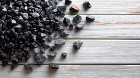 Clean layout of crushed black stones on light wooden background, minimal and editorialの素材