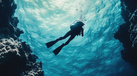 A deep-sea diver floating effortlessly in the calm, crystal-clear waters of a tropical ocean.の素材