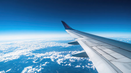 A stunning view of the airplane wing against the vibrant blue sky, capturing the vastness of the world below.の素材