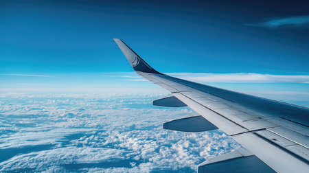 A wing of a commercial airplane high in the sky, with the endless expanse of blue above and below.の素材