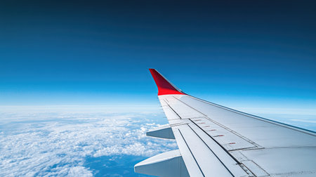 The wing of an airplane in flight, gliding through a cloudless blue sky, with a peaceful and serene atmosphere.の素材