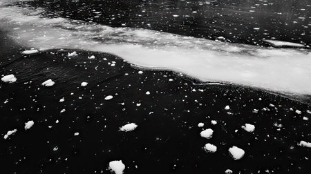 The contrast of dark, deep ice and white snow patches scattered on a frozen lake.の素材