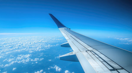 A sleek airplane wing in flight, with a brilliant blue sky creating the perfect backdrop for this aerial view.の素材