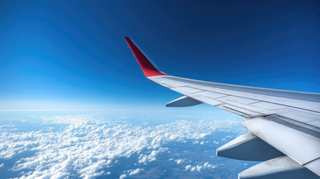 A sleek airplane wing in flight, with a brilliant blue sky creating the perfect backdrop for this aerial view.の素材
