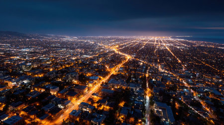 A city at night from above, illuminated streets and buildings forming a glowing patchwork of light, stretching across the urban areaの素材