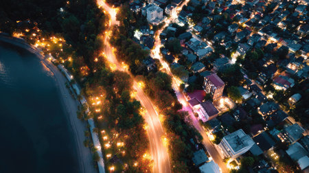 Aerial view of a nighttime city with a network of bright streetlights and illuminated buildings, creating a dynamic and lively urban landscapeの素材