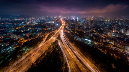 Overhead shot of a modern city at night, with streets and highways lit up, reflecting the city's energy and vibrance in the darknessの素材