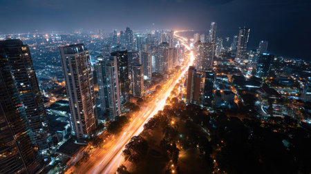 Overhead view of a glowing cityscape at night, with roads and streets filled with shimmering street lights, and tall buildings lit up against the dark skyの素材