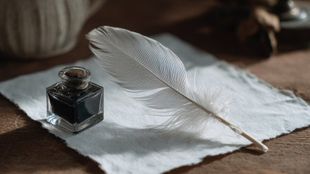 Minimalist desk scene with white feather, square glass ink bottle, and a single sheet of calligraphy paperの素材