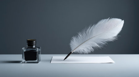Minimalist desk scene with white feather, square glass ink bottle, and a single sheet of calligraphy paperの素材