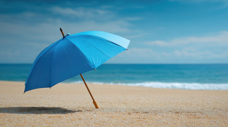 Blue umbrella on a sandy beach with clear sky and ocean in the background, representing vacation and relaxationの素材