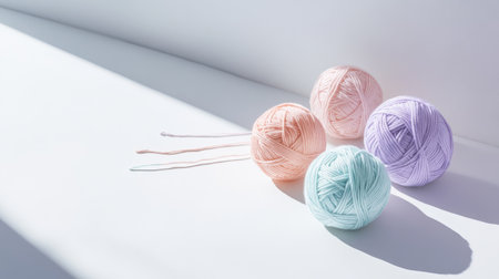 Pastel yarn balls on a white surface with shadows, showcasing soft texture and color harmonyの素材