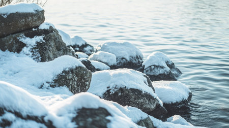 Snow-covered rocky shore beside a lake, combining soft snow textures with rugged natural elementsの素材