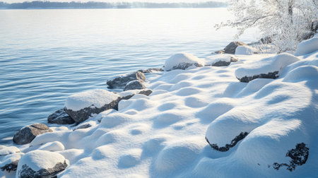 Snow-covered rocky shore beside a lake, combining soft snow textures with rugged natural elementsの素材