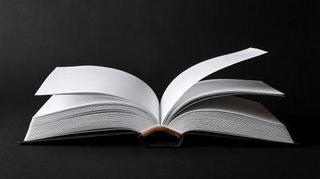 Minimalist composition of an open book with crisp blank pages on matte black backdropの素材