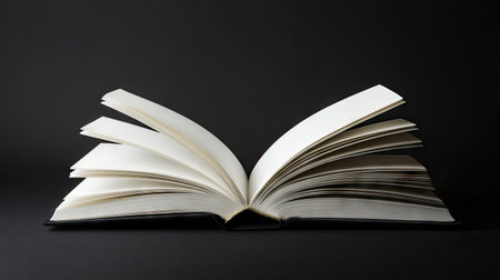 Minimalist composition of an open book with crisp blank pages on matte black backdropの素材