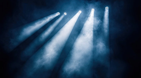 Dark sky with intense white spotlights piercing through the night, creating striking light beams in the air.の素材