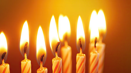 Vibrant glowing birthday candles with yellow-orange flames on simple backdrop, representing festive atmosphere and joyの素材