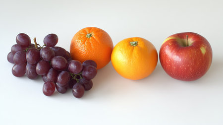 A vibrant assortment of fresh fruits, including oranges, apples, and grapes, arranged on a clean white background, showcasing vivid colors and texturesの素材