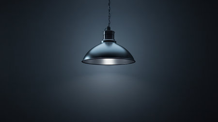 Industrial-style ceiling lamp fixture lit against a dark ceiling, casting subtle light and shadow for an urban ambiance.の素材