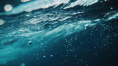 Macro shot of tiny air bubbles rising through a fresh, blue water wave, capturing clarity and purity with gentle movement.の素材