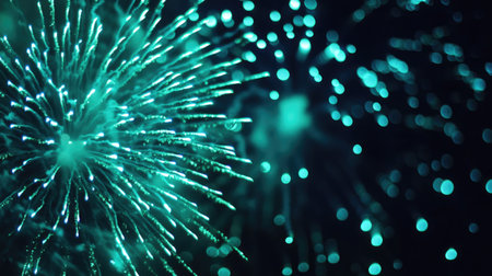 Bright green and blue fireworks illuminate the night, casting vibrant colors against the darknessの素材
