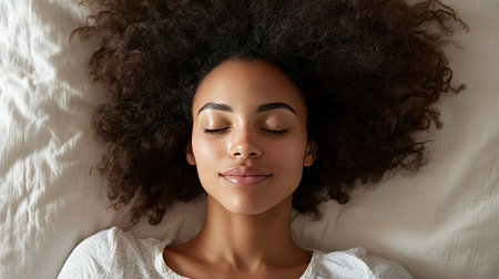 Overhead view of a woman in pajamas sleeping peacefully on her back, her face relaxed and serene on a comfortable pillowの素材