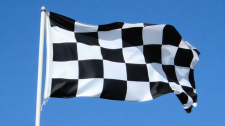 Close-up of a waving checkered flag against a clear blue sky, symbolizing victory and racing spirit.の素材