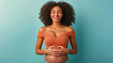 Woman making a heart gesture over her belly, representing self-love and care, with a neutral background.の素材