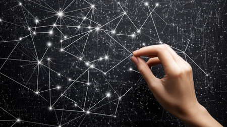 A hand adjusting a pin in a complex network of connections displayed on a black corkboard.の素材