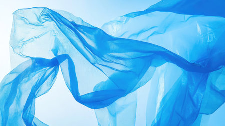 Close-up of a blue plastic bag fluttering in the wind against a bright skyの素材