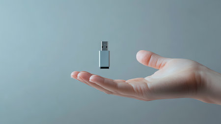 A dynamic shot of a hand extending a USB flash drive toward the camera, with a clean backdrop.の素材