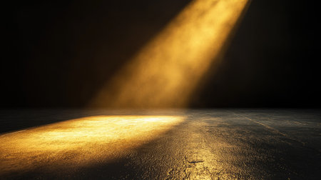 A single golden spotlight shining down on an empty floor, highlighting textures in the darkの素材