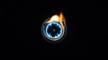 Sharp focus on a circular gas burner flame glowing blue against a minimal black backgroundの素材