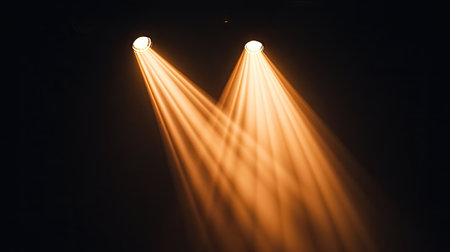 Two warm-toned spotlights overlapping their beams, creating a gradient effect against a black backdropの素材