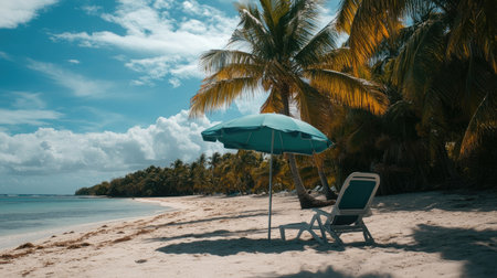 An empty beach chair and sun umbrella on a remote island beach, palm trees swaying in the background.の素材