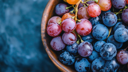 A close-up of an assortment of grapes in a bowl, with some grapes cut in half to reveal their juicy interior, creating an appetizing display.の素材