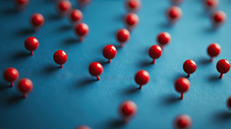 A scattering of red pushpins over a blue paper surface, creating a striking contrast.の素材