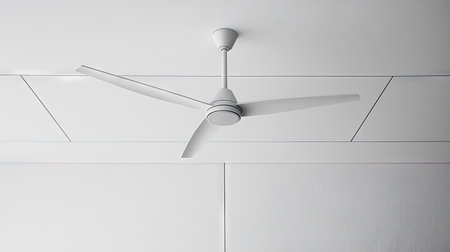 White ceiling fan with three blades, isolated against a modern white ceiling, with clear and clean lines.の素材