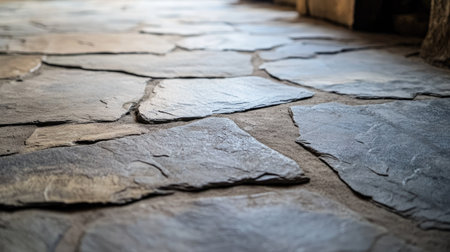 A close-up of textured stone flooring in a rustic home, showing the uneven surface and natural imperfections in each stone tile.の素材