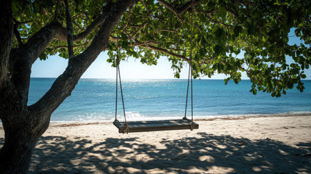 A picturesque beach scene featuring a swing hanging from a leafy tree, overlooking the sparkling ocean under a bright blue sky, creating a serene atmosphere.の素材