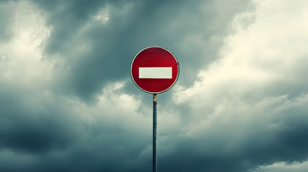 A solitary no entry sign stands tall against a backdrop of dark and turbulent clouds, capturing a striking moment that evokes feelings of caution and unease.の素材